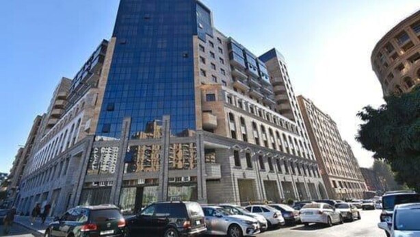A multi-story building with a modern glass facade and a mix of architectural styles. - Apartment near in Republic square  (Yerevan)