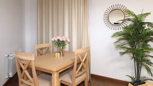 A dining area with a wooden table and chairs, a vase with flowers, a mirror on the wall, and a potted plant. - Apartment near in Republic square  (Yerevan)