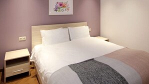 A bedroom with a bed, nightstand, and a wall-mounted artwork. - Apartment near in Republic square  (Yerevan)