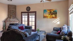 A living room with a fireplace, two sofas, a coffee table, and a ceiling fan.