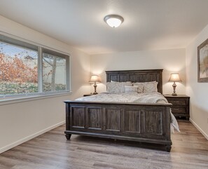 Una camera da letto con un letto in legno, due comodini con lampade, una finestra con persiane e un quadro appeso al muro.