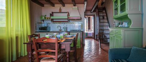 A cozy kitchen with wooden furniture, a dining table, and a staircase leading to another level.