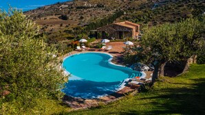 A private pool with lounge chairs and umbrellas, surrounded by lush greenery and a hillside view. - Poggio Pozzetti (Lascari)