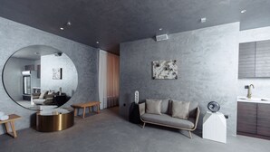 A modern living room with a round mirror, a round coffee table, a sofa, a white cabinet, and a large painting on the wall. - ABK Hotel (Atyrau)