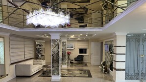 A spacious living area with a chandelier, a sofa, and a coffee table. - ABK Hotel (Atyrau)