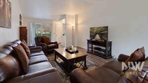 Una sala de estar moderna con sofás de cuero, una mesa de centro y un televisor sobre un mueble de madera.
