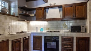 A kitchen with wooden cabinets, a gas stove, an oven, and a microwave. - VILLA SERENA x6 Beautiful villa surrounded by nature, with swimming pool just 1 km from Cortona (Cortona)
