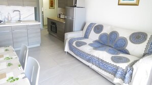 Una cocina moderna con electrodomésticos de acero inoxidable, un comedor con mesa y sillas, y un sofá con cojines decorativos.