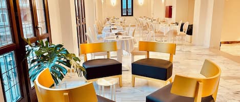 Un vestíbulo de hotel con una larga recepción, varias mesas de comedor y sillas.