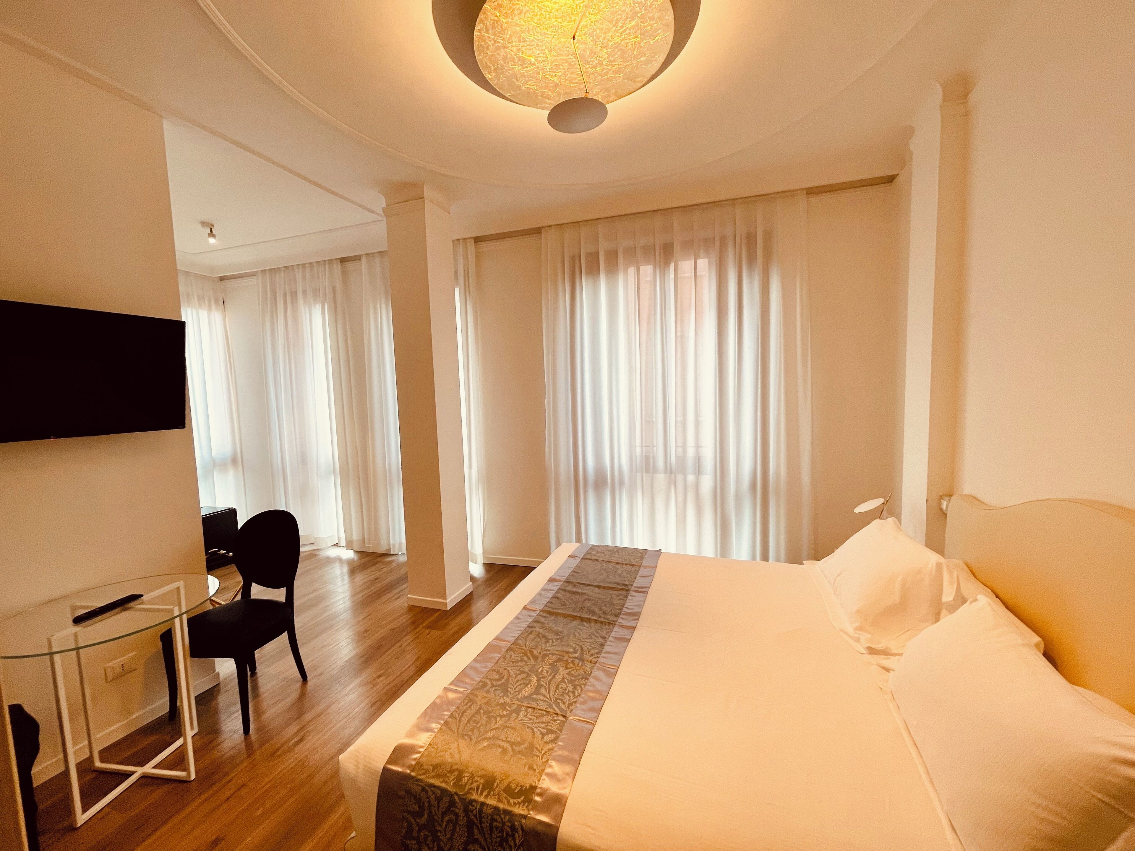 Una habitación de hotel con una cama grande, un escritorio con una silla y un televisor montado en la pared.