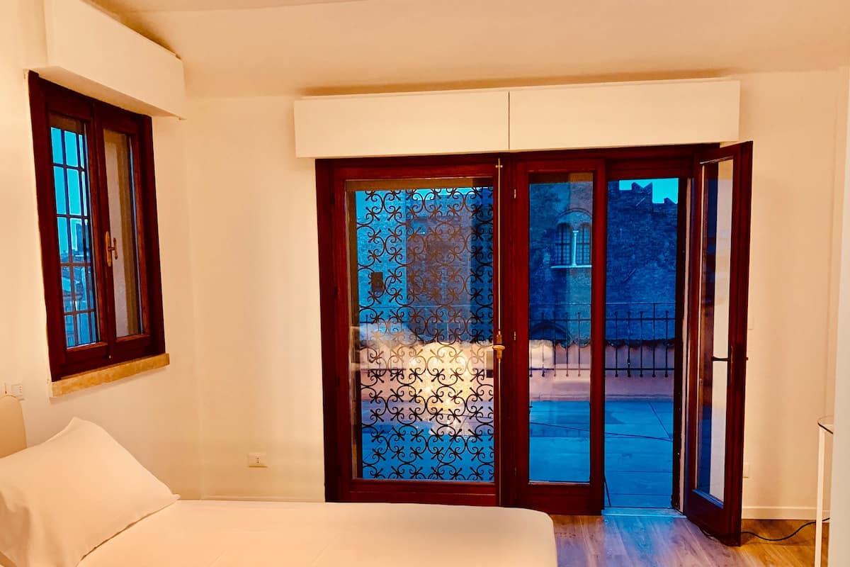 Ein Schlafzimmer mit Bett, Fenster und einer Tür, die nach draußen führt.