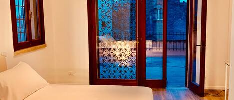 Un dormitorio con cama, ventana y puerta que da al exterior.