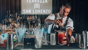 Un barman darrere d'una barra amb un cartell que diu "TERRAZZA SAN LORENZO".