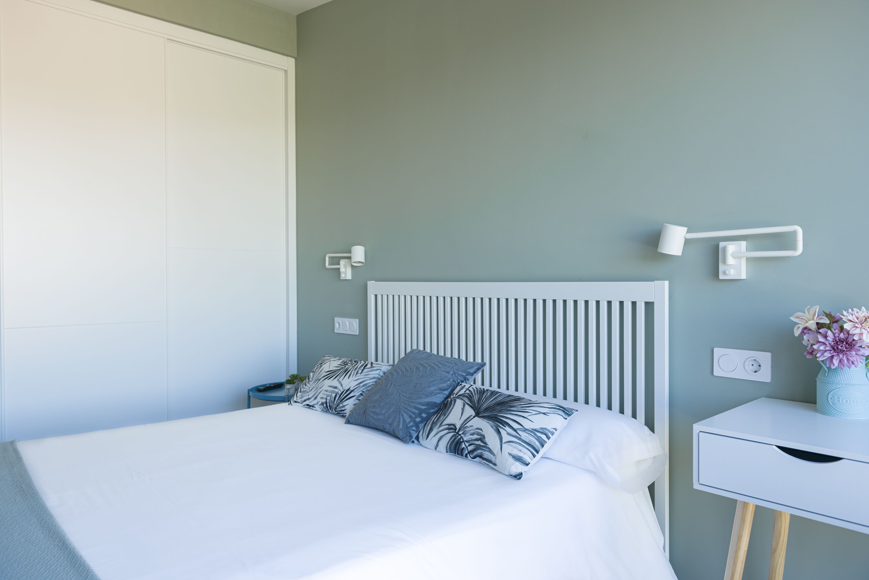 Une chambre à coucher avec un lit, une table de chevet avec une lampe et une prise de courant fixée au mur.