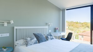 Un dormitorio moderno con cama, mesita de noche y escritorio con silla.