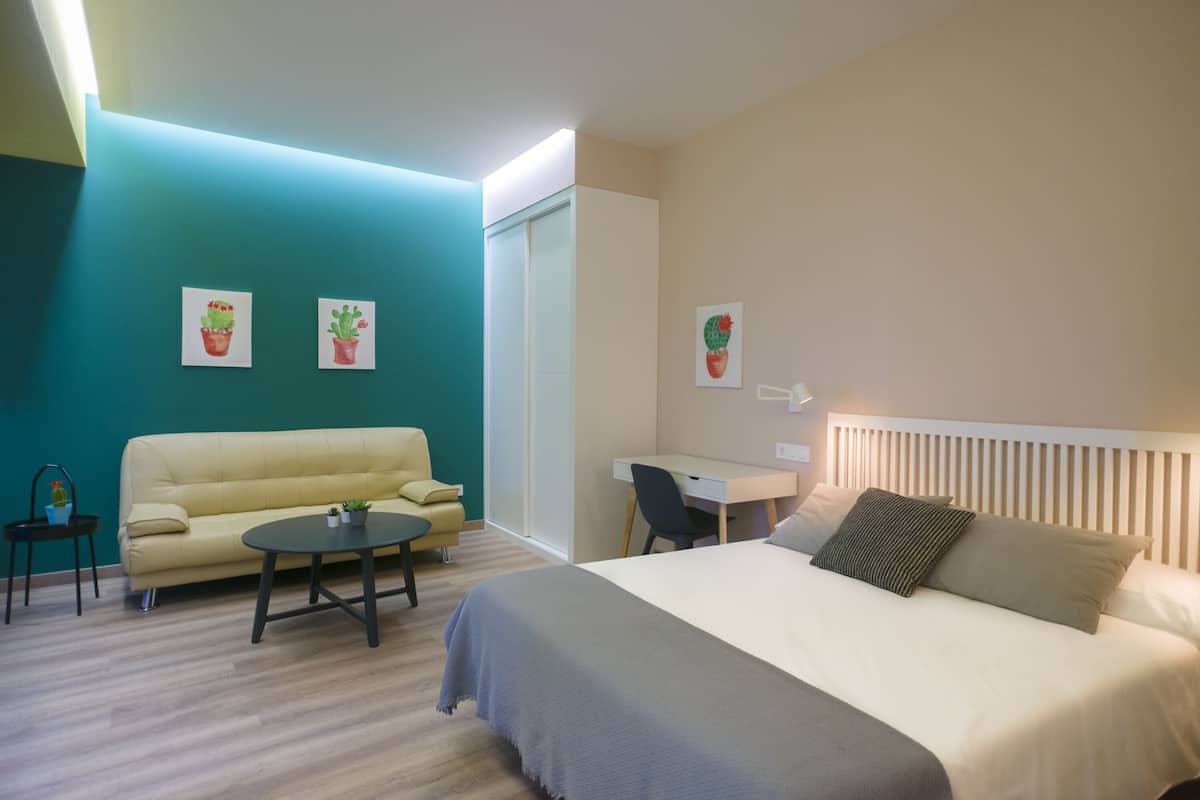 Une chambre d’hôtel moderne, équipée d’un lit, d’un bureau, d’un canapé et de deux plantes en pot accrochées au mur.