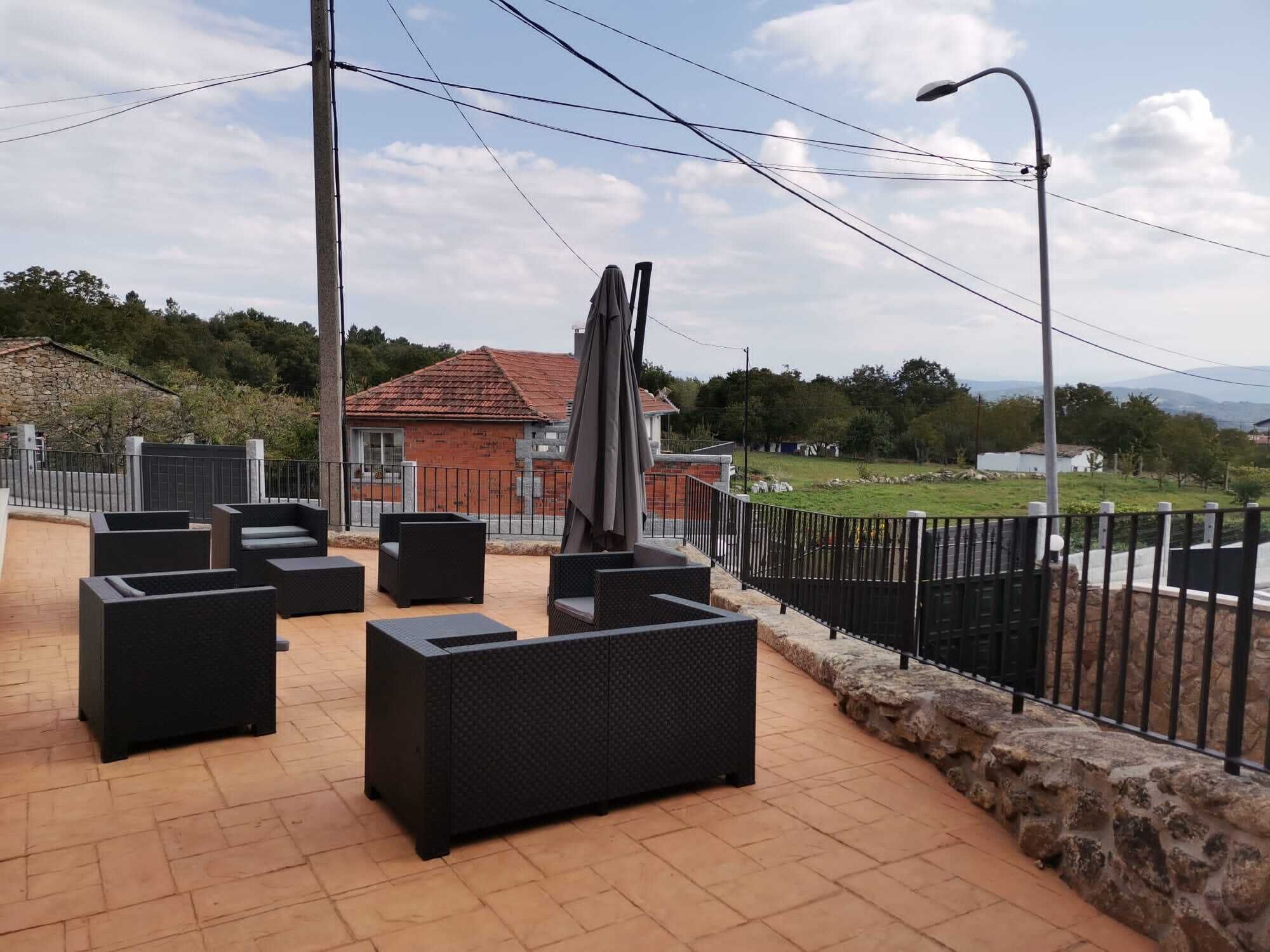 Un patio al aire libre con mobiliario de mimbre negro y pared de piedra.