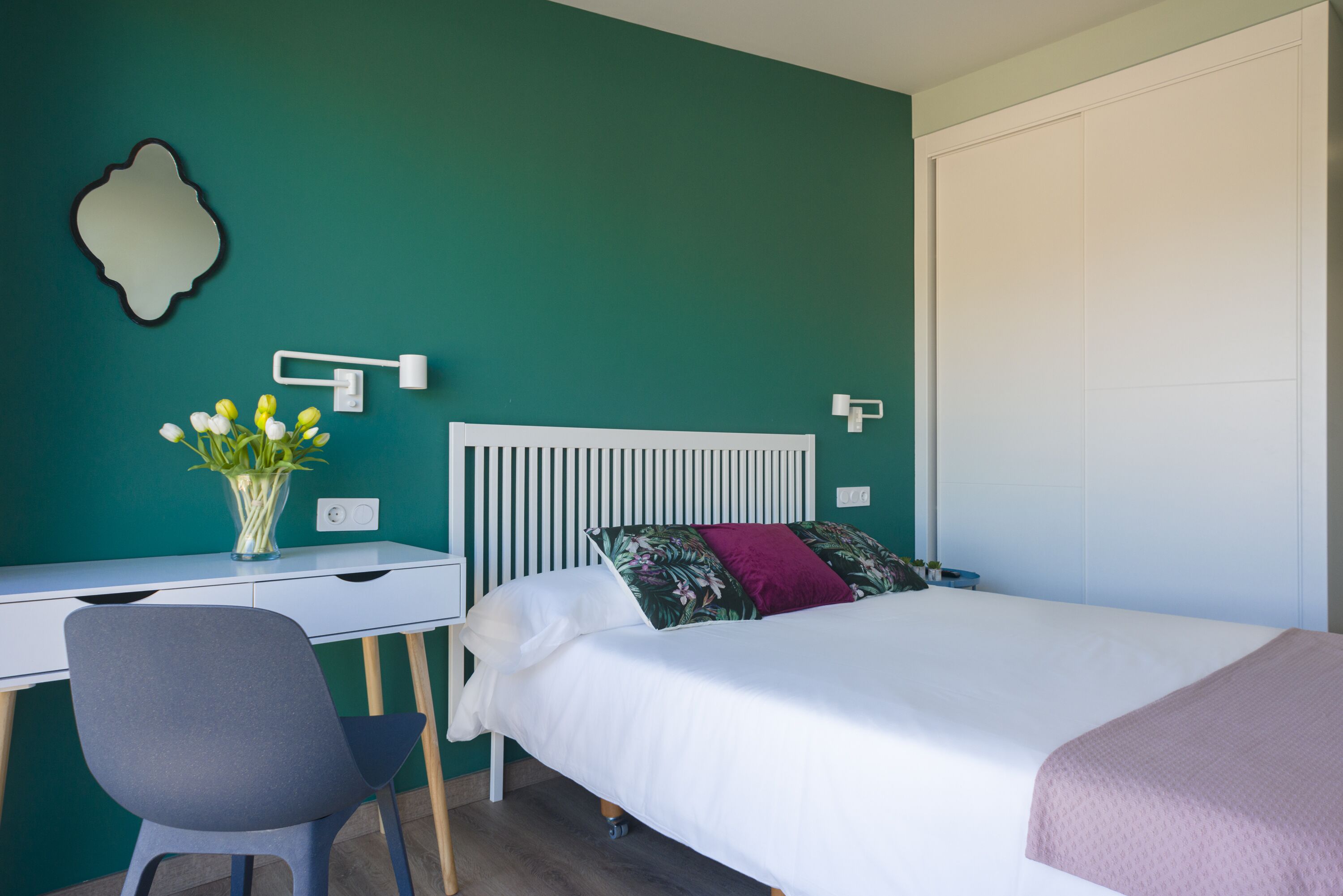 Un dormitorio con una cama, un escritorio y una silla.