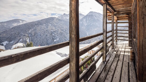 Ein hölzerner Balkon mit Blick auf verschneite Berge.