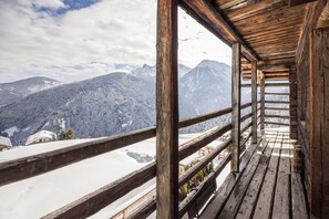 Un balcon en bois offrant une vue sur des montagnes enneigées.