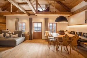 Un intérieur en bois avec un canapé, une table à manger, des chaises et une vue par la fenêtre.