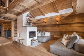 L’intérieur d’une cabane en rondins, avec une cheminée, un canapé et des poutres en bois.