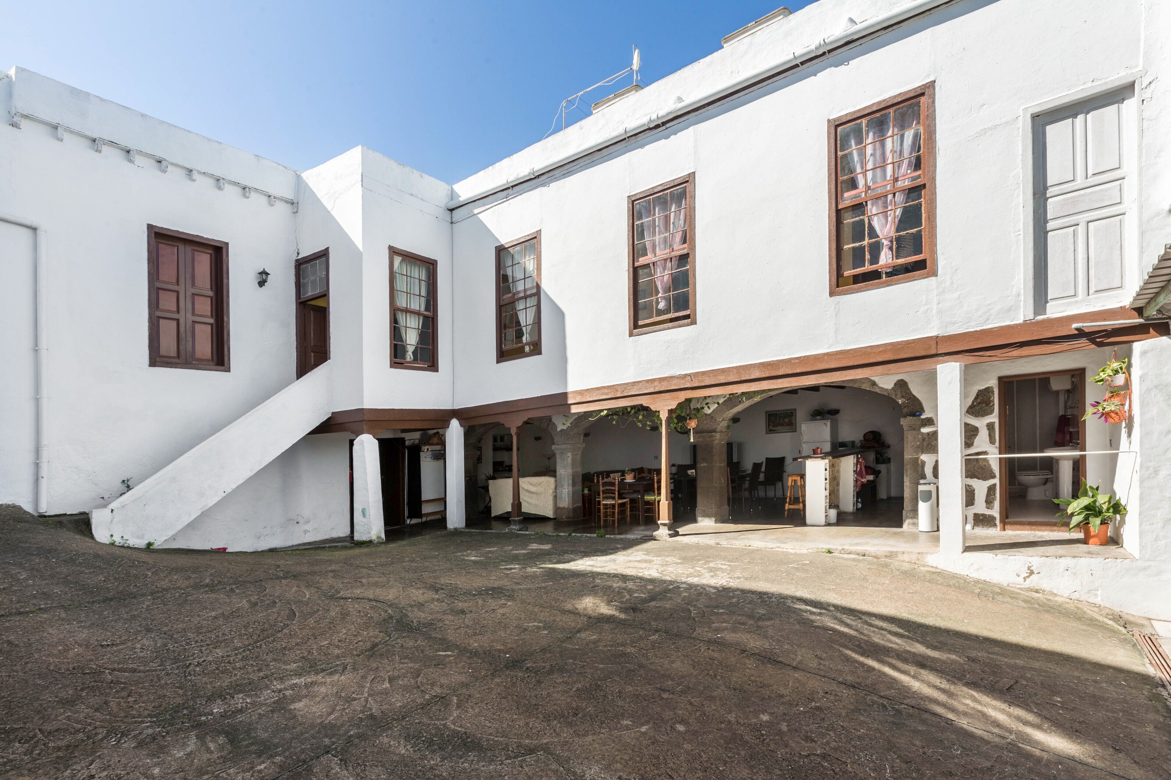 Un edificio blanco con varias ventanas y un área de estar al aire libre cubierta.