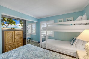 A bedroom with a bunk bed, a dresser, and a view of a beach through a window. - Top-floor direct oceanfront 2/2 with a private balcony, heated pool and beach access (New Smyrna Beach)