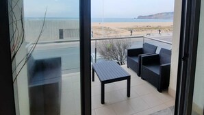 A balcony with a view of the beach and a clear sky. - DUPLEX facing the sea, ideal for your family vacation (Nazaré)