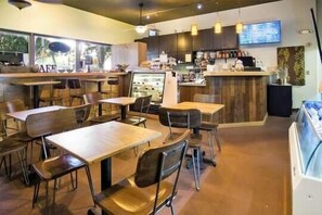 Café interior with seating areas, a counter, and display case.