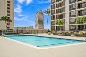 Relax by the pool surrounded by palm trees and lounge chairs.