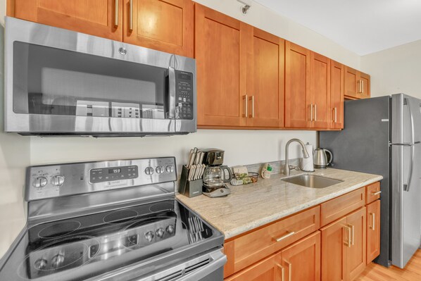 Enjoy cooking in this well-lit kitchen with a microwave, oven, and wooden cabinets.