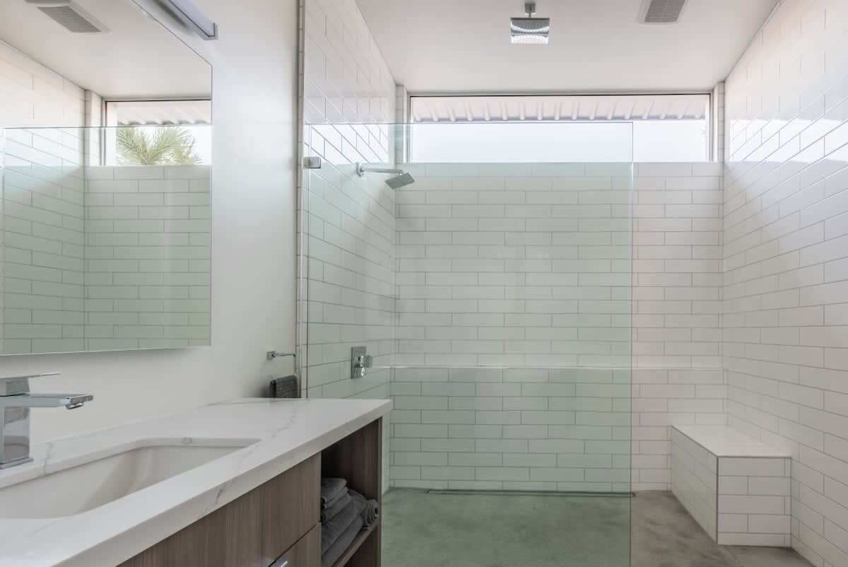 Un bagno moderno con box doccia in vetro, lavandino e specchio.