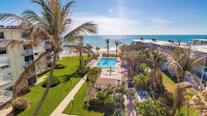 Un hôtel doté d’une piscine, de palmiers et offrant une vue sur l’océan.
