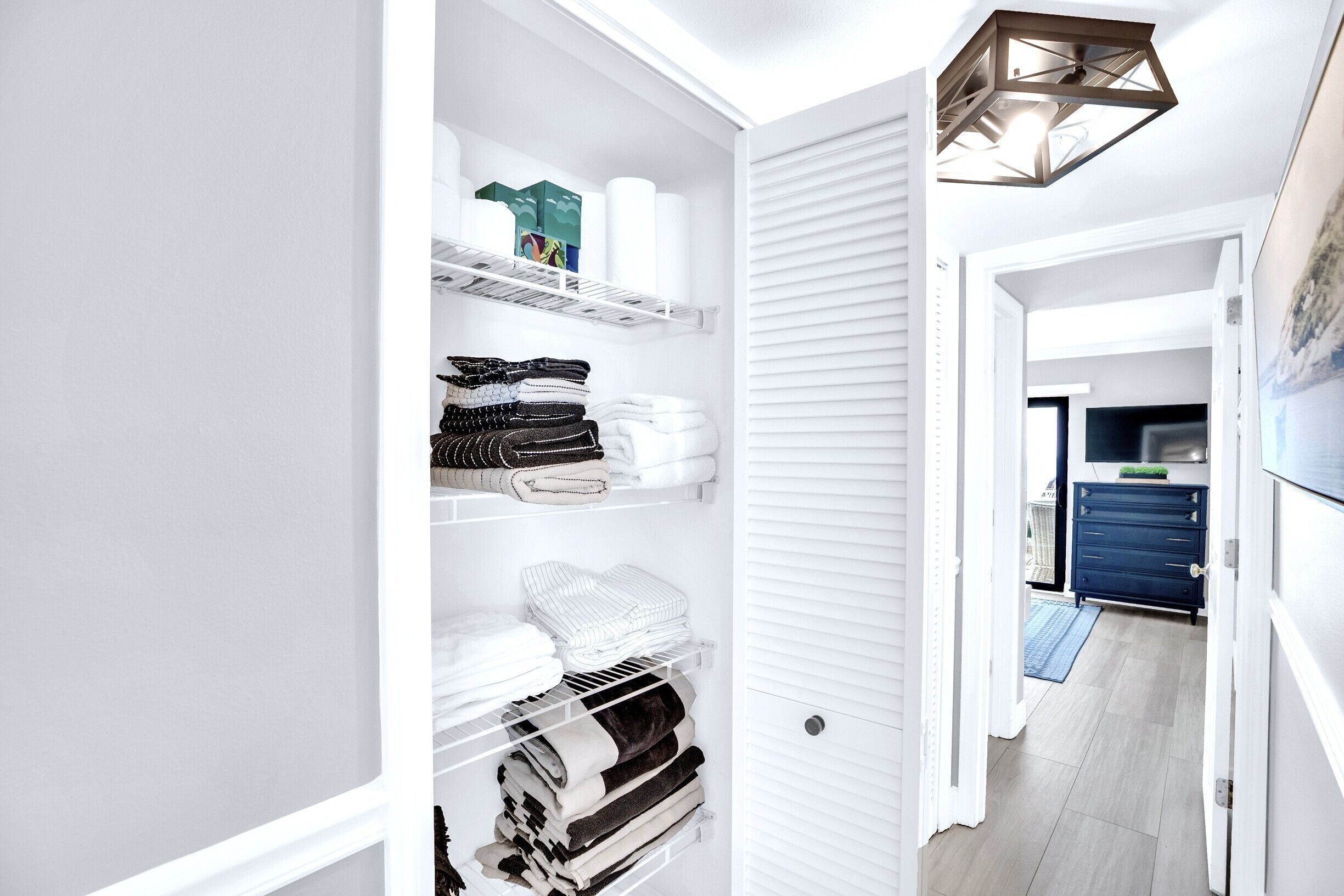 A walk-in closet with shelves, a hanging rod, and a door leading to a hallway.