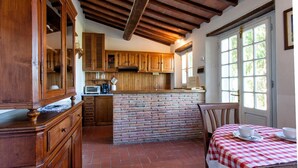 Una cocina rústica con armarios de madera, una isla de ladrillo y un mantel a cuadros.