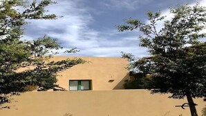 Un bâtiment à la façade plate, doté d’une petite fenêtre et entouré de verdure.