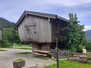 A rustic wooden building with a slanted roof, a wooden bench, and a fence.