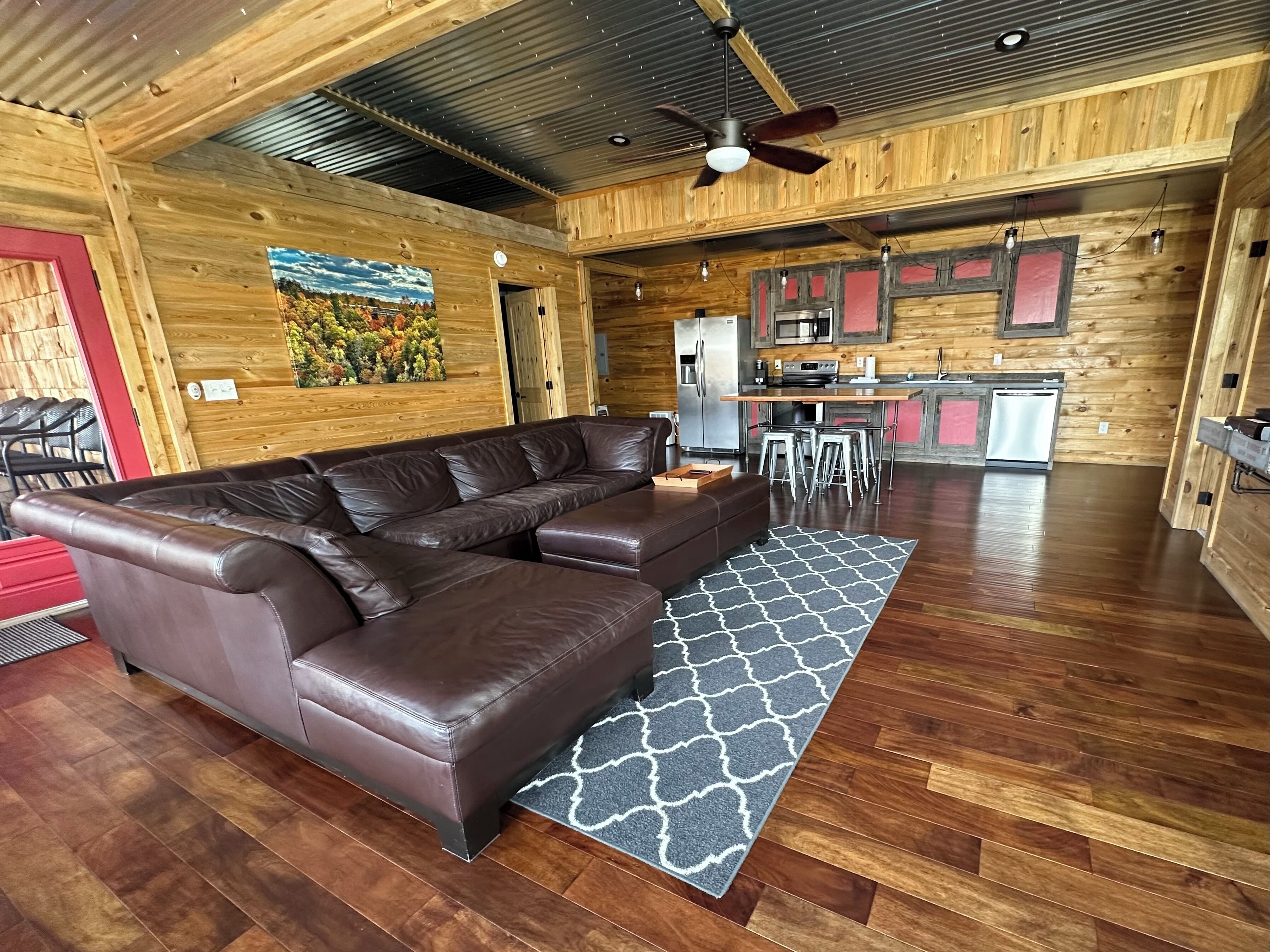 A spacious living area with a sectional sofa, a kitchen with modern appliances, and a dining area with bar stools.