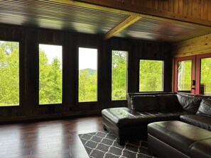 Une pièce dotée d’une grande fenêtre, d’un canapé en cuir et d’un plancher en bois.