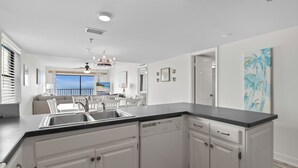 Een moderne keuken met witte kasten, een zwart aanrechtblad en een inbouw vaatwasser.