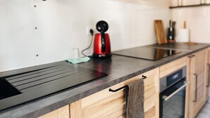 Eine moderne Küche mit schwarzer Arbeitsplatte, Holzschränken, einem roten Wasserkocher und einem klaren Glas.