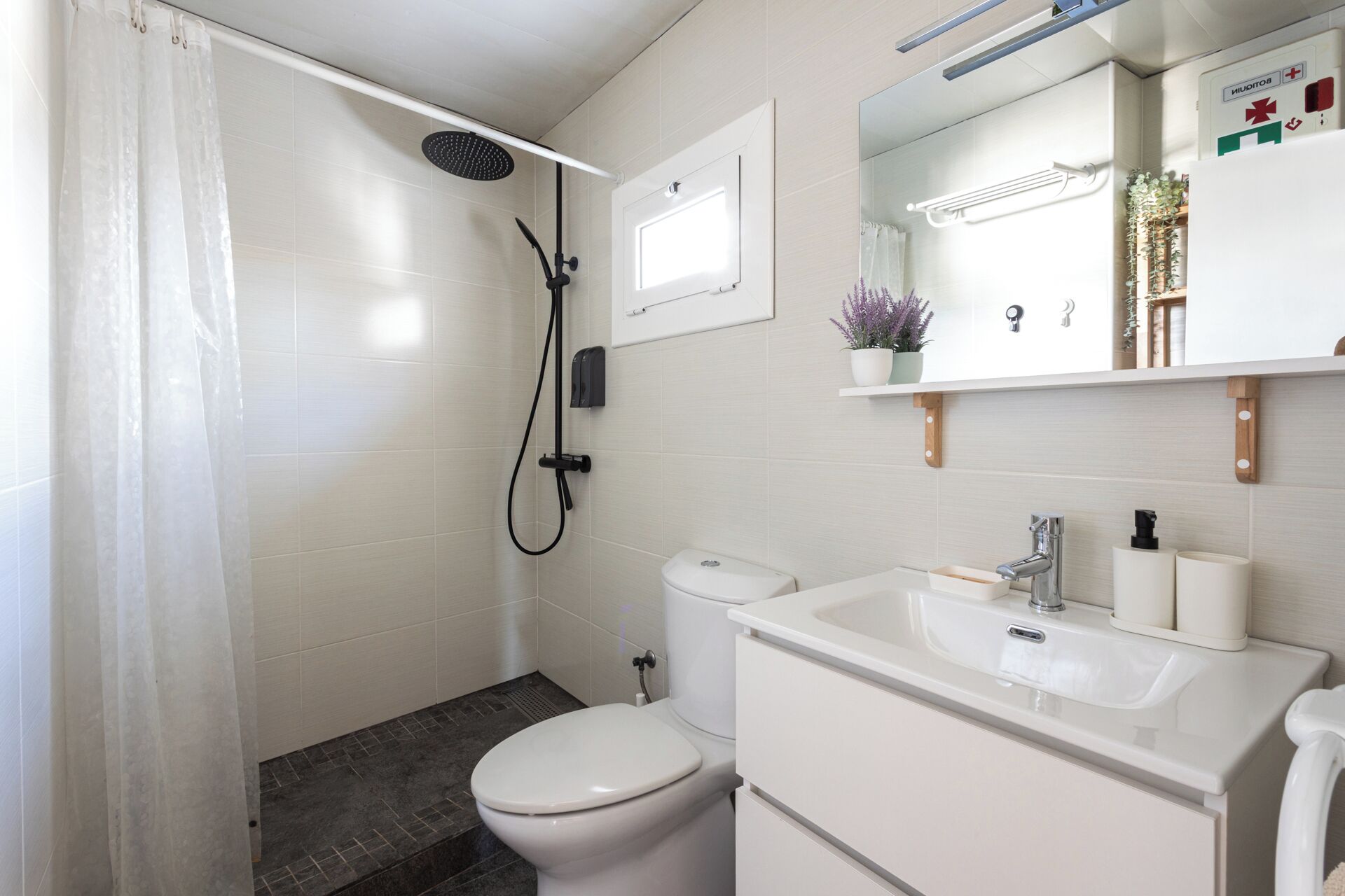 Un bagno con doccia, WC, lavandino e specchio.