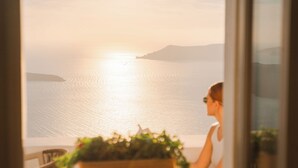 Une personne assise près d’une fenêtre, donnant sur une mer calme, avec des reliefs terrestres visibles au loin.