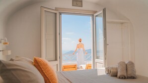 Une chambre avec un grand lit, un balcon avec vue et une chaise en bois.