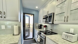 Uma cozinha moderna com armários brancos, micro-ondas, torradeira e fogão.
