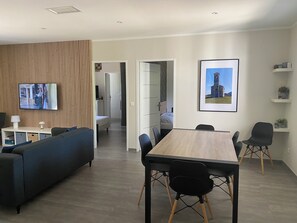 Ein modernes Wohnzimmer mit einer Couch, einem Fernseher und einem Essbereich mit Tisch und Stühlen.