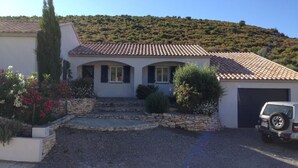 A house with a tiled roof, a driveway, and a parked car.