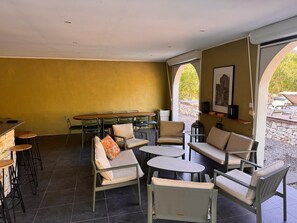 Un amplio espacio interior con una mesa de comedor, múltiples sillas y una zona de estar con sofás y mesitas.