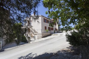 Un edificio de dos pisos con fachada de piedra, una escalera que conduce a la entrada y un cielo despejado.